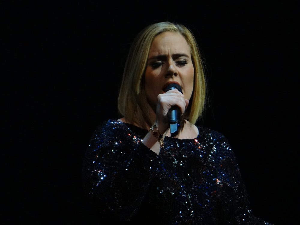Adele zingt met een handmicrofoon tijdens een concert in Nashville in 2016