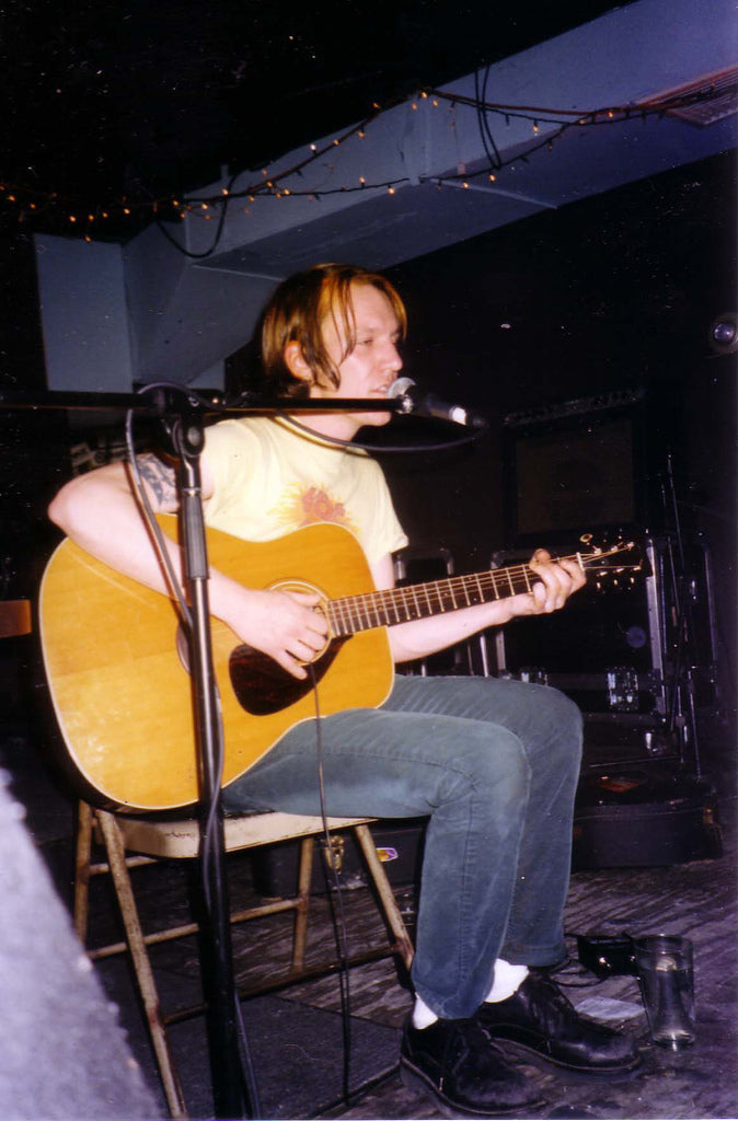Elliott Smith zit op een stoel en zingt met een akoestische gitaar tijdens een optreden in Brownies in New York.