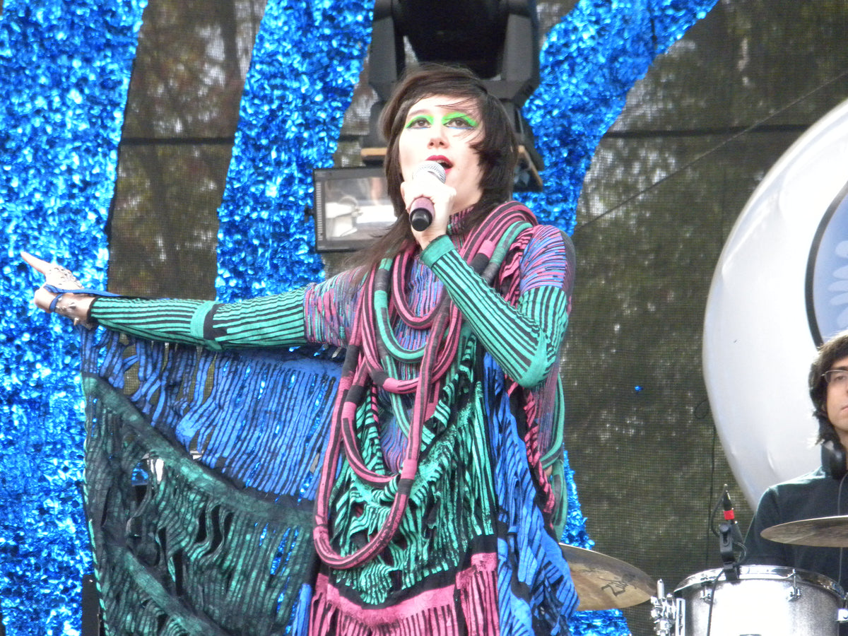 Karen O van Yeah Yeah Yeahs zingt met een microfoon en een uitgestrekte arm tijdens Bumbershoot in 2009.