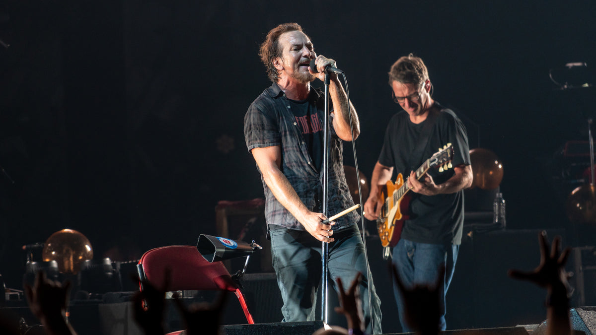 Eddie Vedder zingt met Pearl Jam, met een gitarist naast hem op het podium.