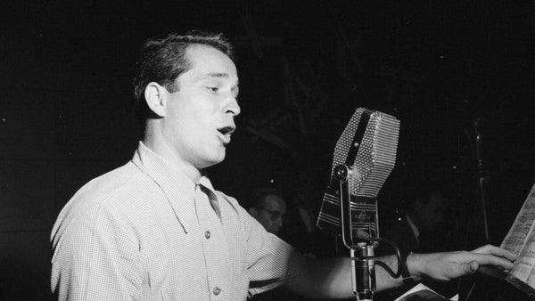 Perry Como zingt bij een microfoon naast een lessenaar met bladmuziek