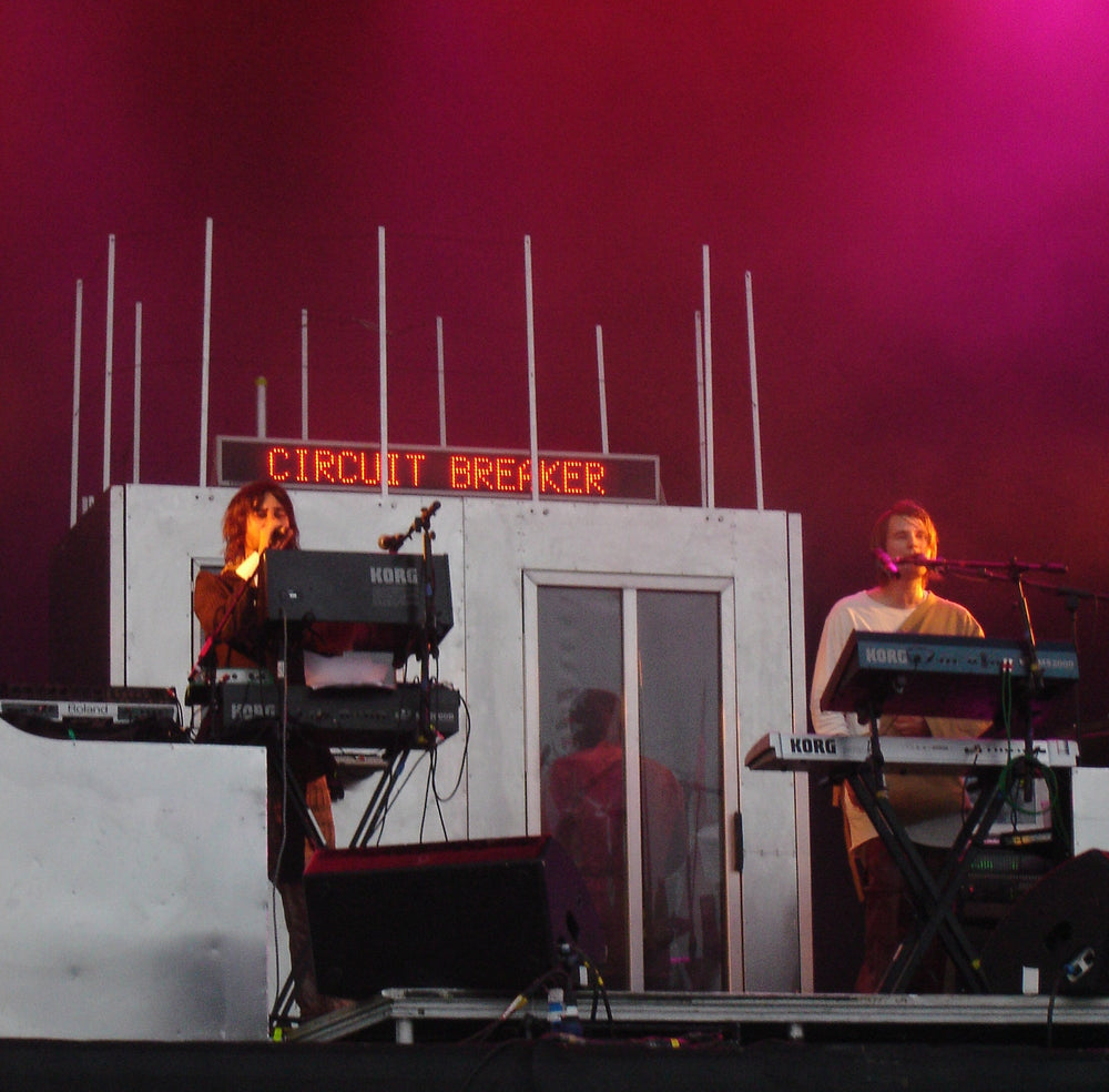 Röyksopp achter synthesizers op een podium met roze verlichting tijdens Glastonbury 2005.