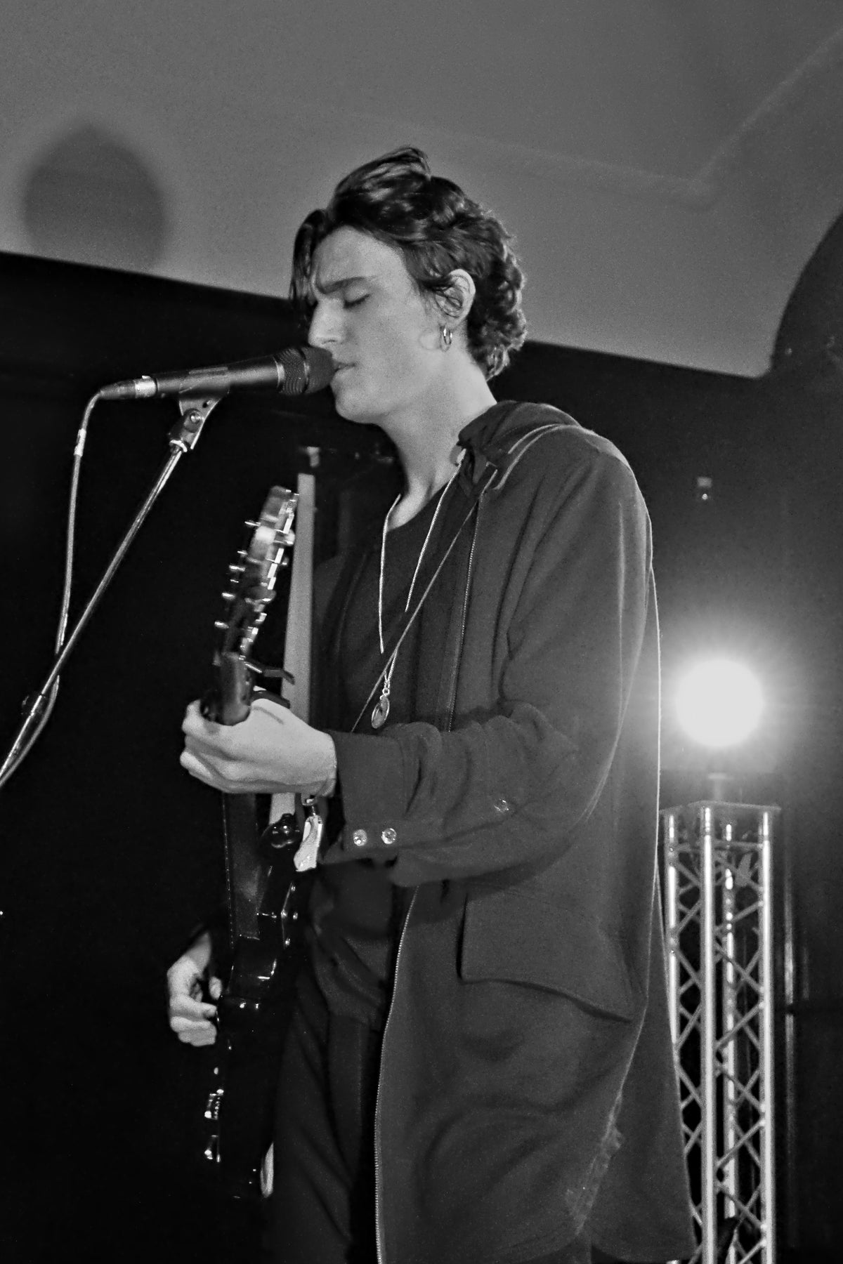 Zwart-witfoto van Tamino die met gesloten ogen zingt en gitaar speelt tijdens Waves Vienna in 2018.