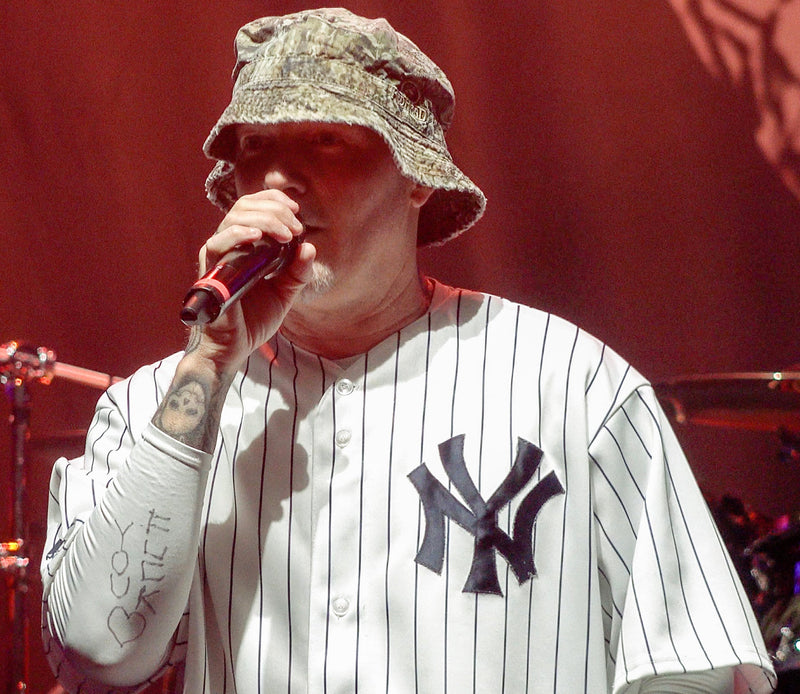 Fred Durst zingt met een microfoon en camouflagehoed tijdens een concert van Limp Bizkit in 2019.