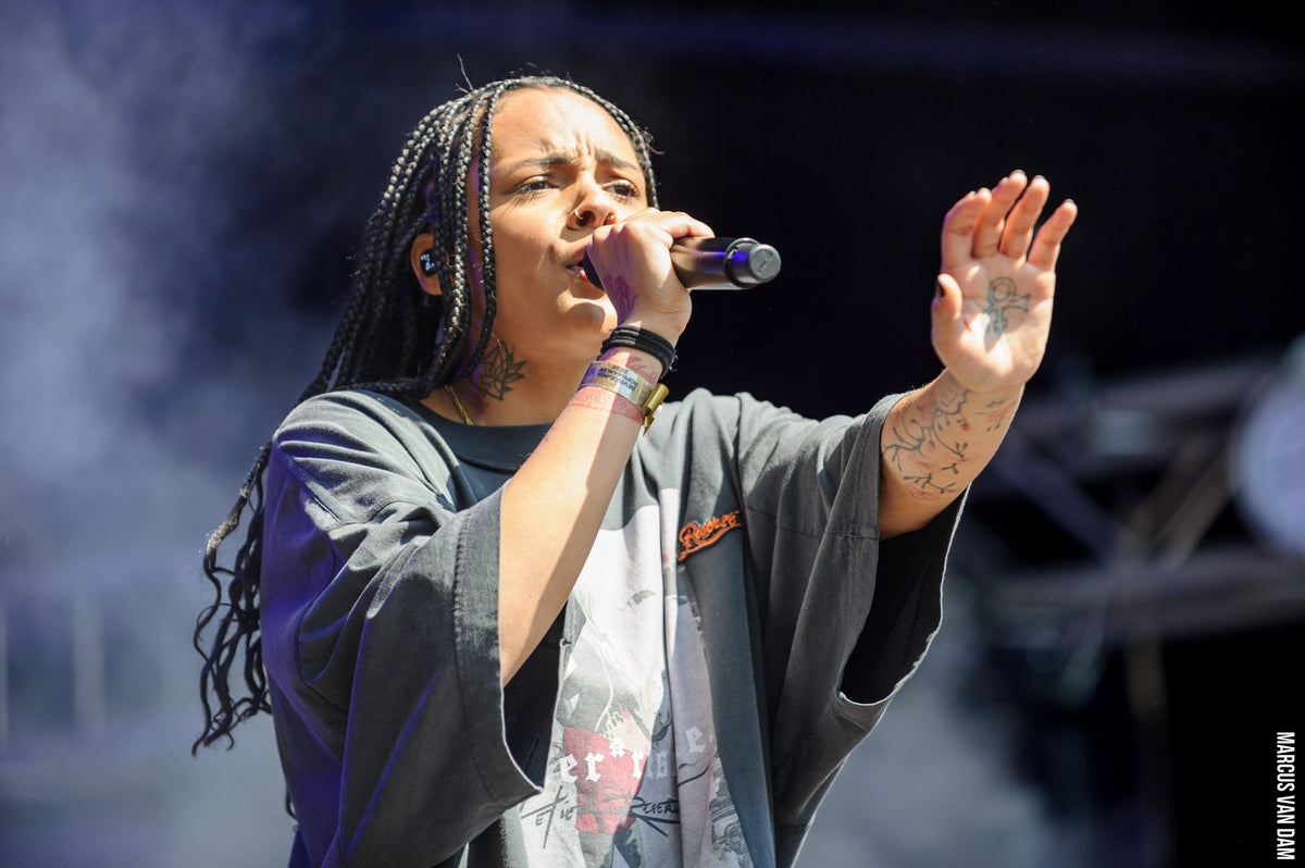 Zoë Livay zingt met een handmicrofoon en opgeheven hand op Bevrijdingspop 2024.