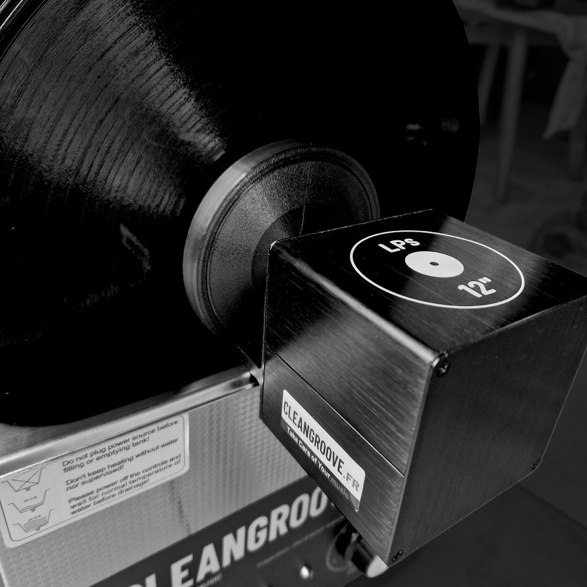 Een zwarte CleanGroove houder met "LPS 12"" op een vinylplaat in de ultrasone reiniger.