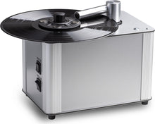 Zilveren platenspeler met vinylplaat, reinigingsarm en aan de zijkant "MOTOR" en "VACUUM" schakelaars.