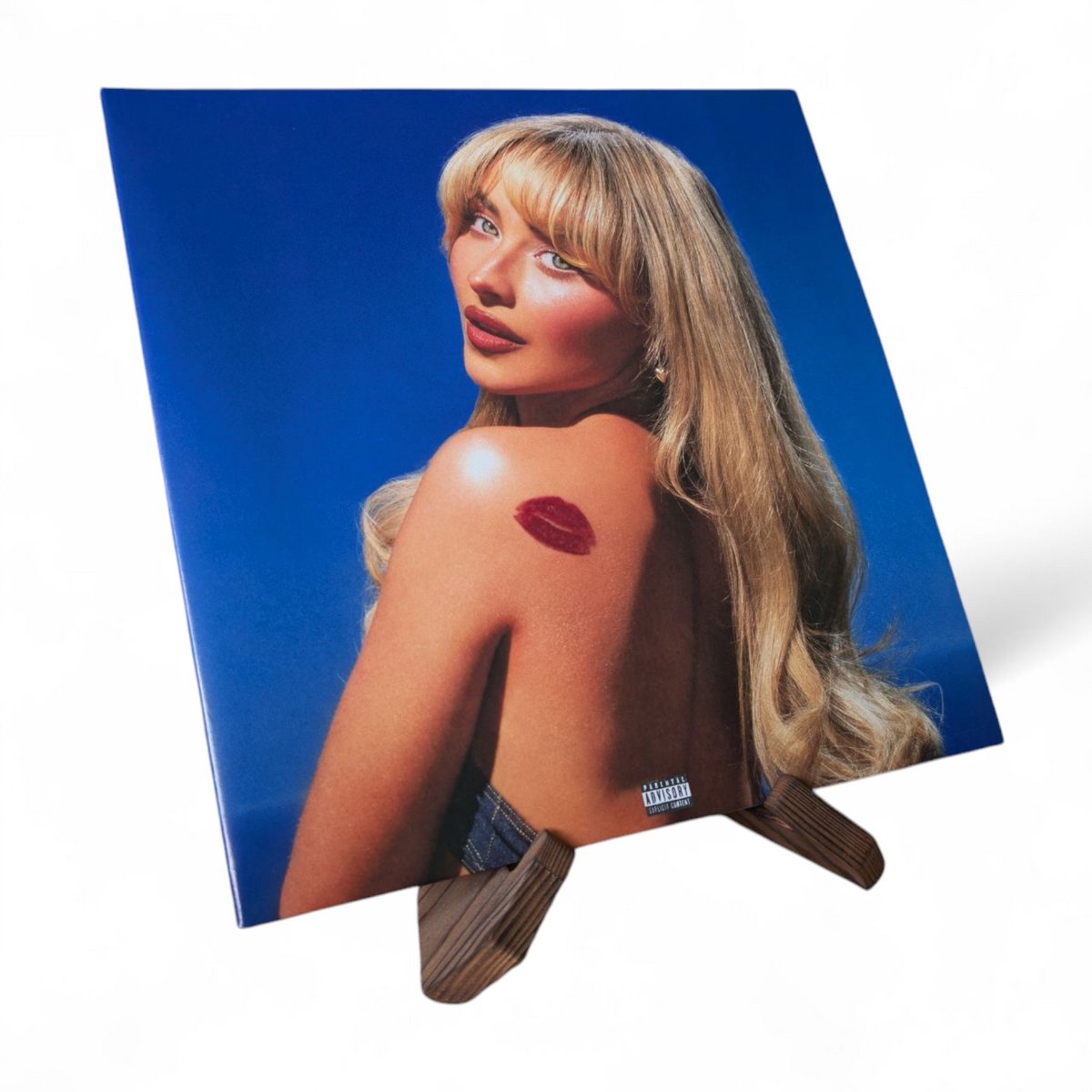 Albumcover met blondharige vrouw met rode lippenafdruk op haar schouder, tegen een blauwe achtergrond.