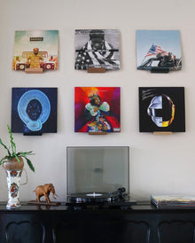Zes platenhoezen hangen aan de muur, waaronder 'Ancient Future' van Protoje, 'Long Live A$AP' van A$AP Rocky en 'Random Access Memories' van Daft Punk.