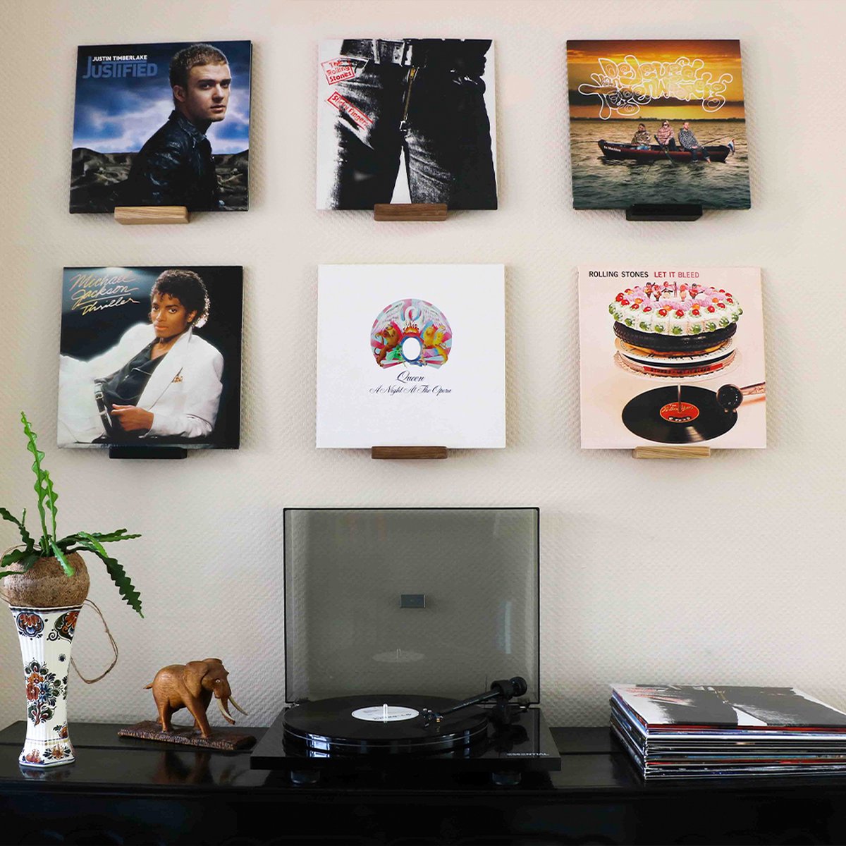 Negen platenhoezen hangen aan de muur, waaronder 'Justified' van Justin Timberlake, 'Bad' van Michael Jackson en 'Let It Bleed' van The Rolling Stones.