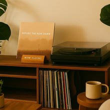 LP "Before The New Dawn" op een houten kastje naast een platenspeler. "Now Playing" standaard.